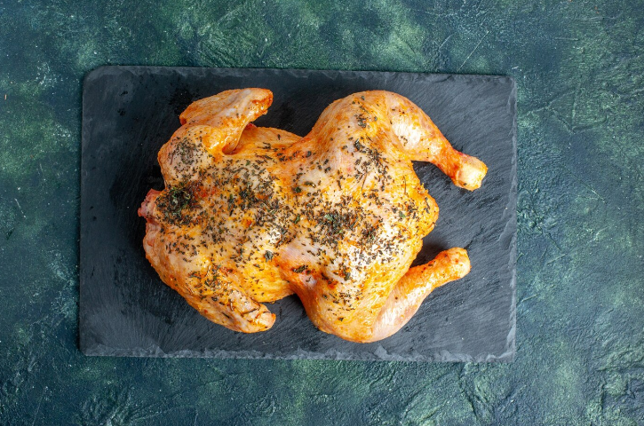 Delicious baked crack chicken topped with melted cheese, crispy bacon, and fresh herbs served on a white plate.